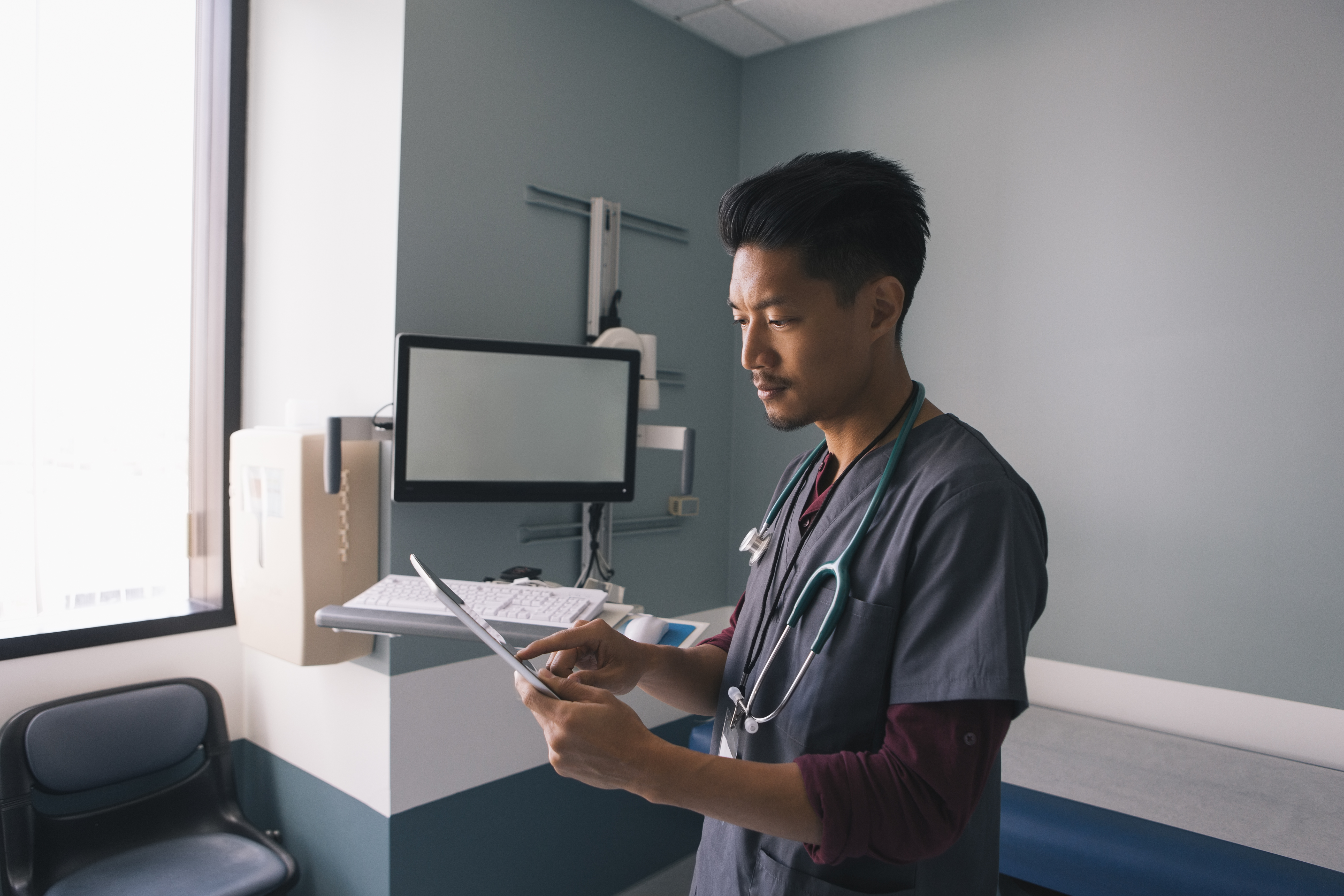 Asian male reviewing patient records on Ipad