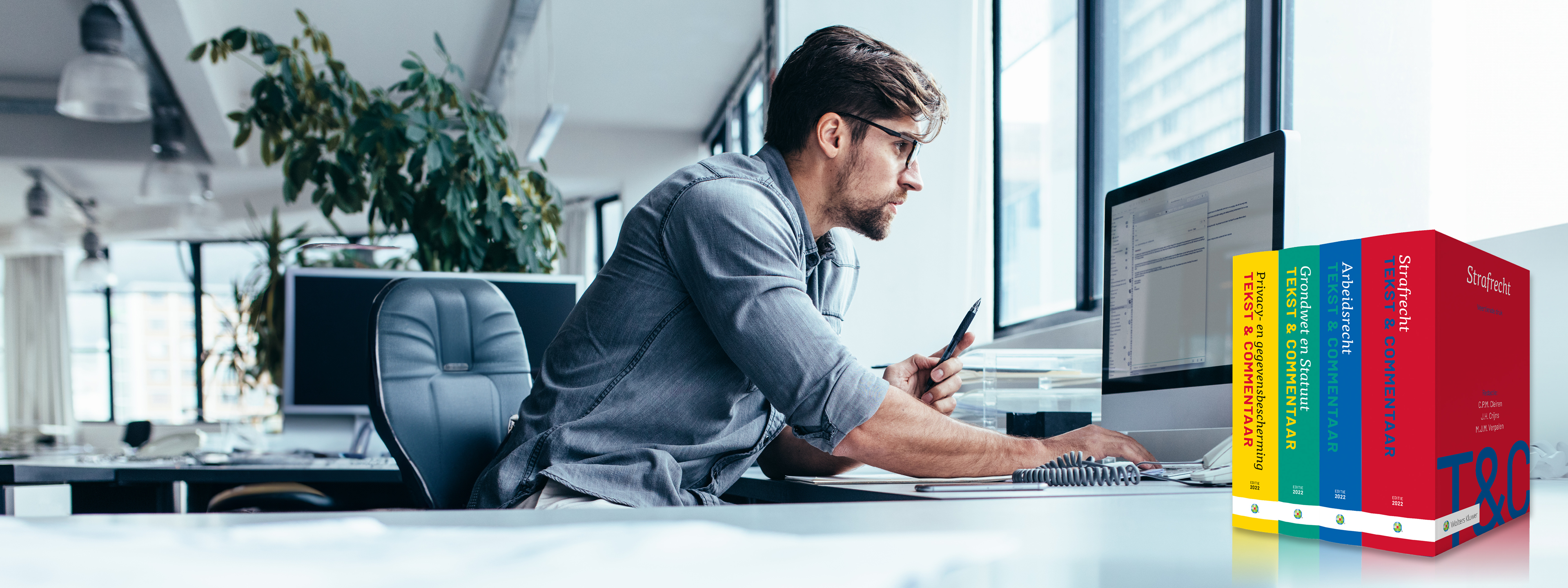 Man werkt op computer naast Tekst & Commentaar uitgaven