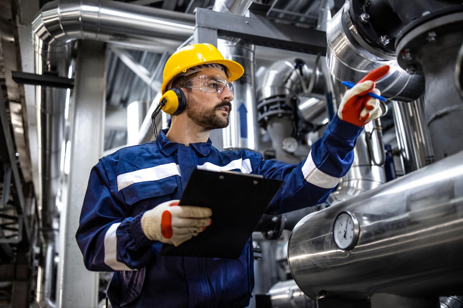 Refinery worker with checklist checking pressure and gas production in factory.