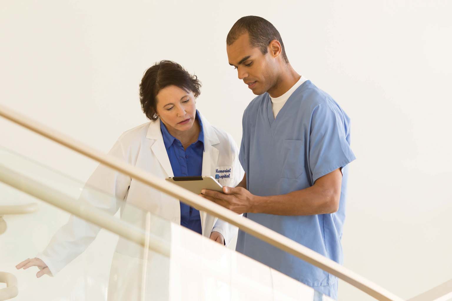 doctor and nurse looking at tablet on stairway