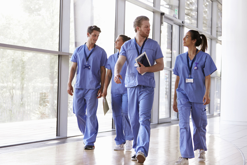 Four healthcare workers in scrubs walking in corridor