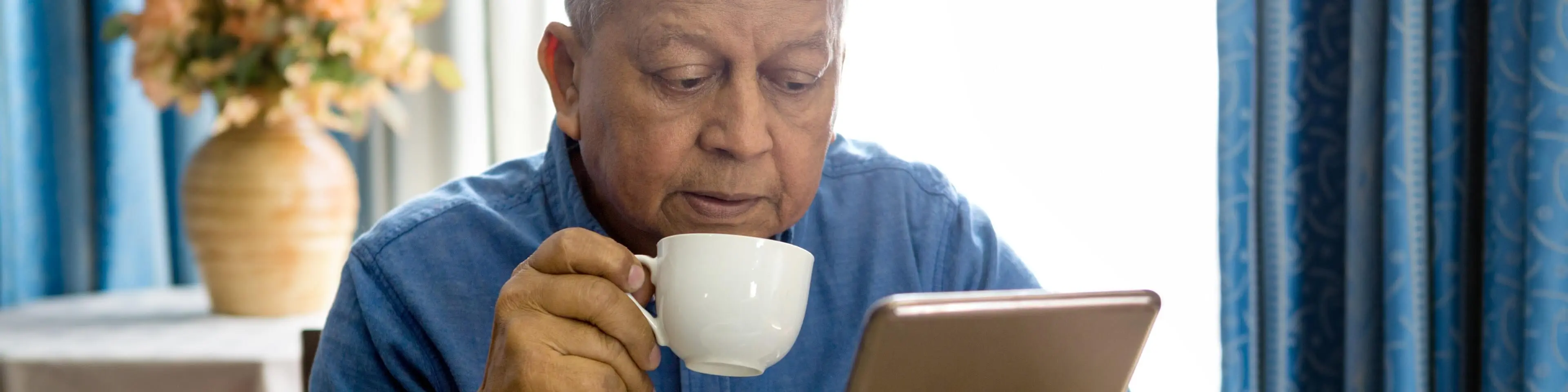 Patient drinking coffee while browsing with a tablet