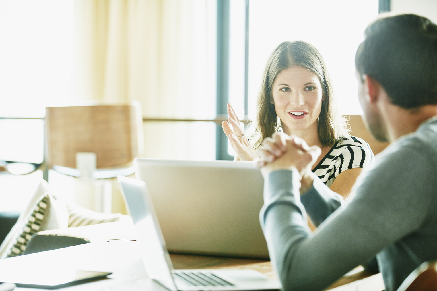 Smiling businesswoman in discussion with colleague at office conference room table