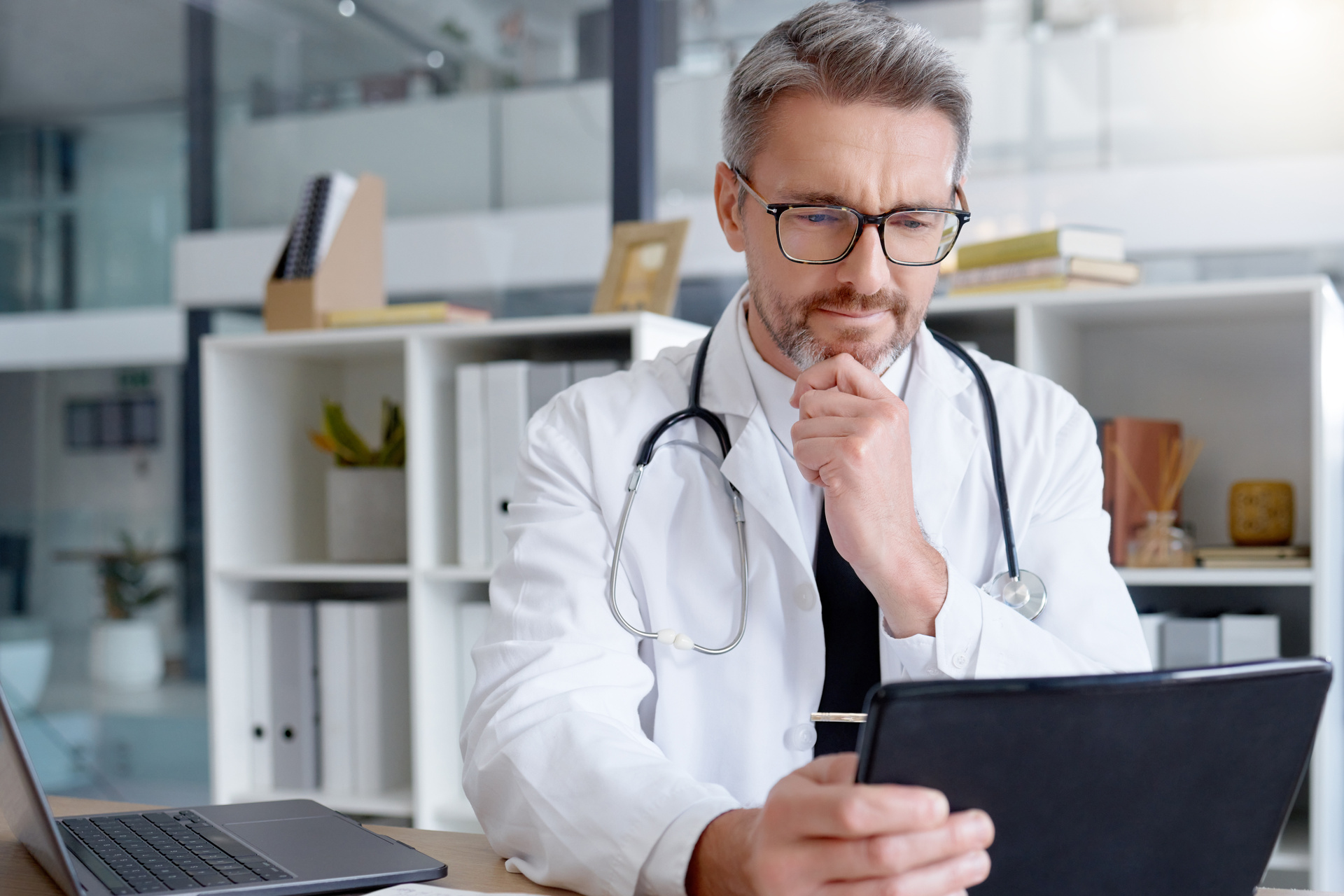 White male doctor using tablet to review medical records