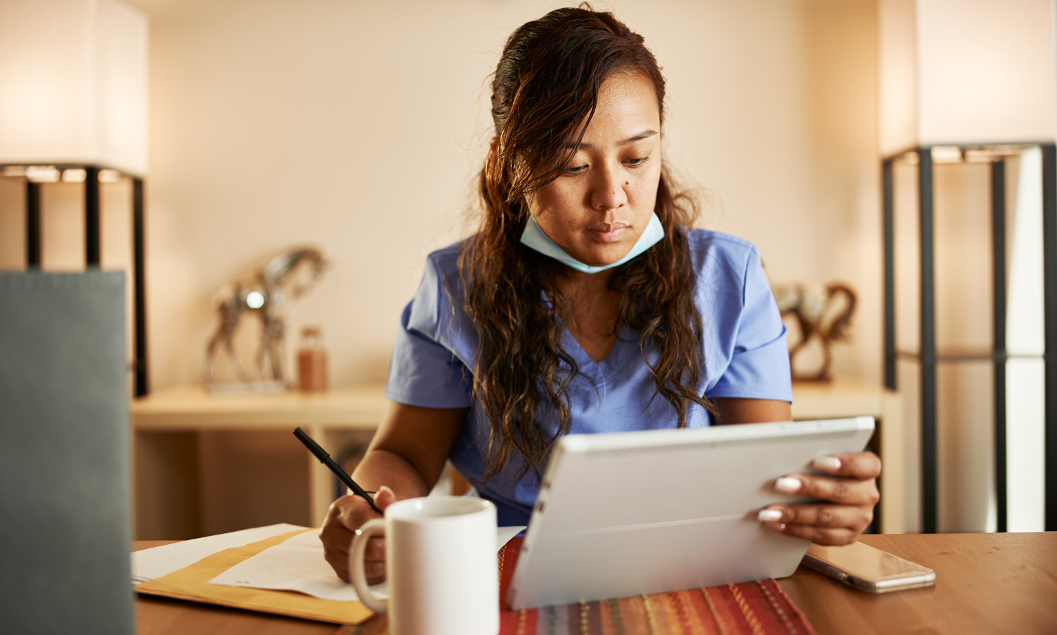 Filipina nurse working from home doing paperwork and using tablet