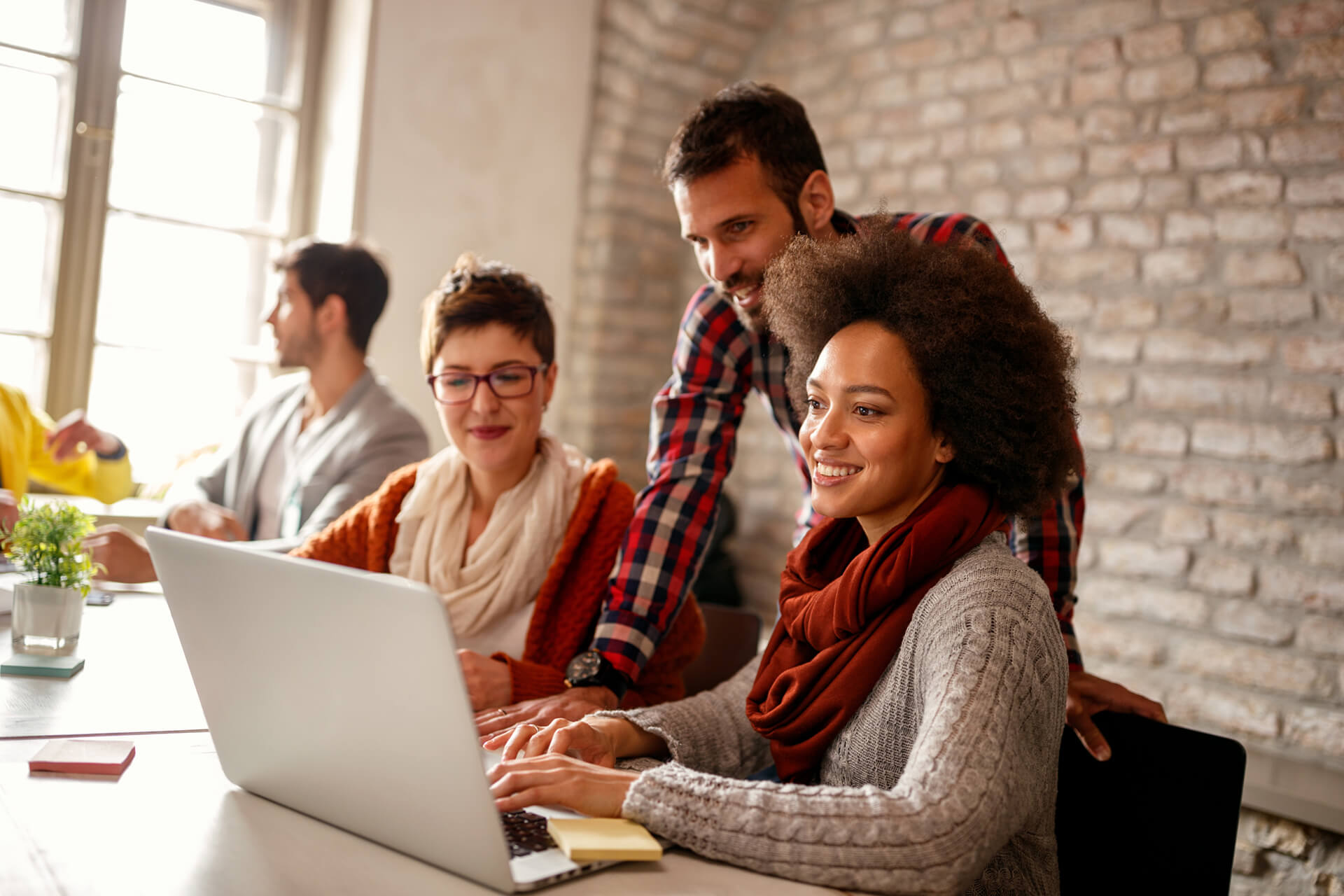 Three people gather around a laptop.