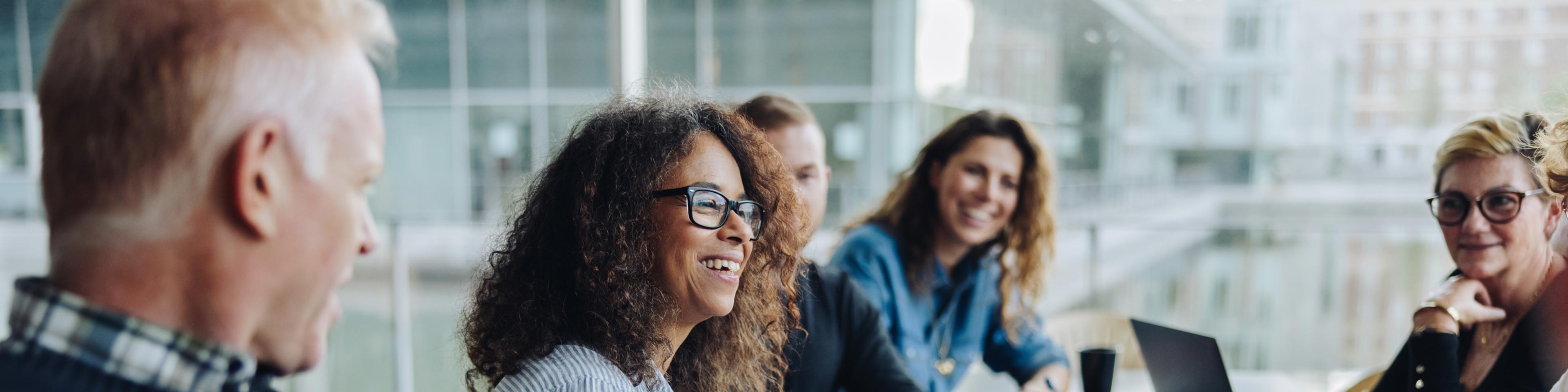 a group of business professionals gathered around a conference table smiling and laughing