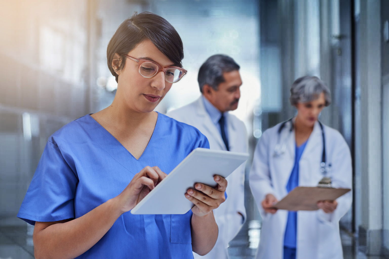 Female medical tech using tablet in hospital hallway