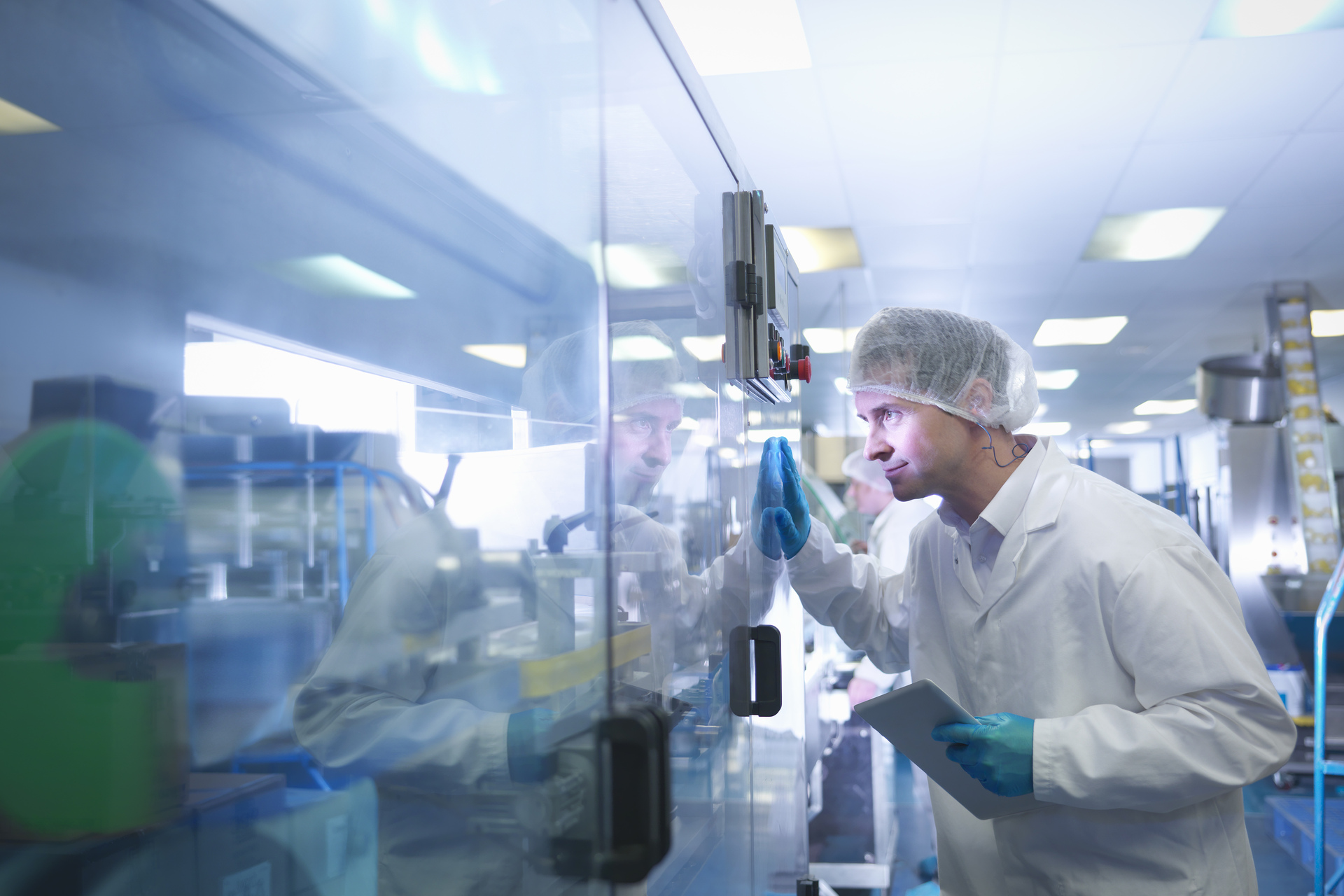 Worker inspecting tablets as they are put into packaging in pharmaceutical factory