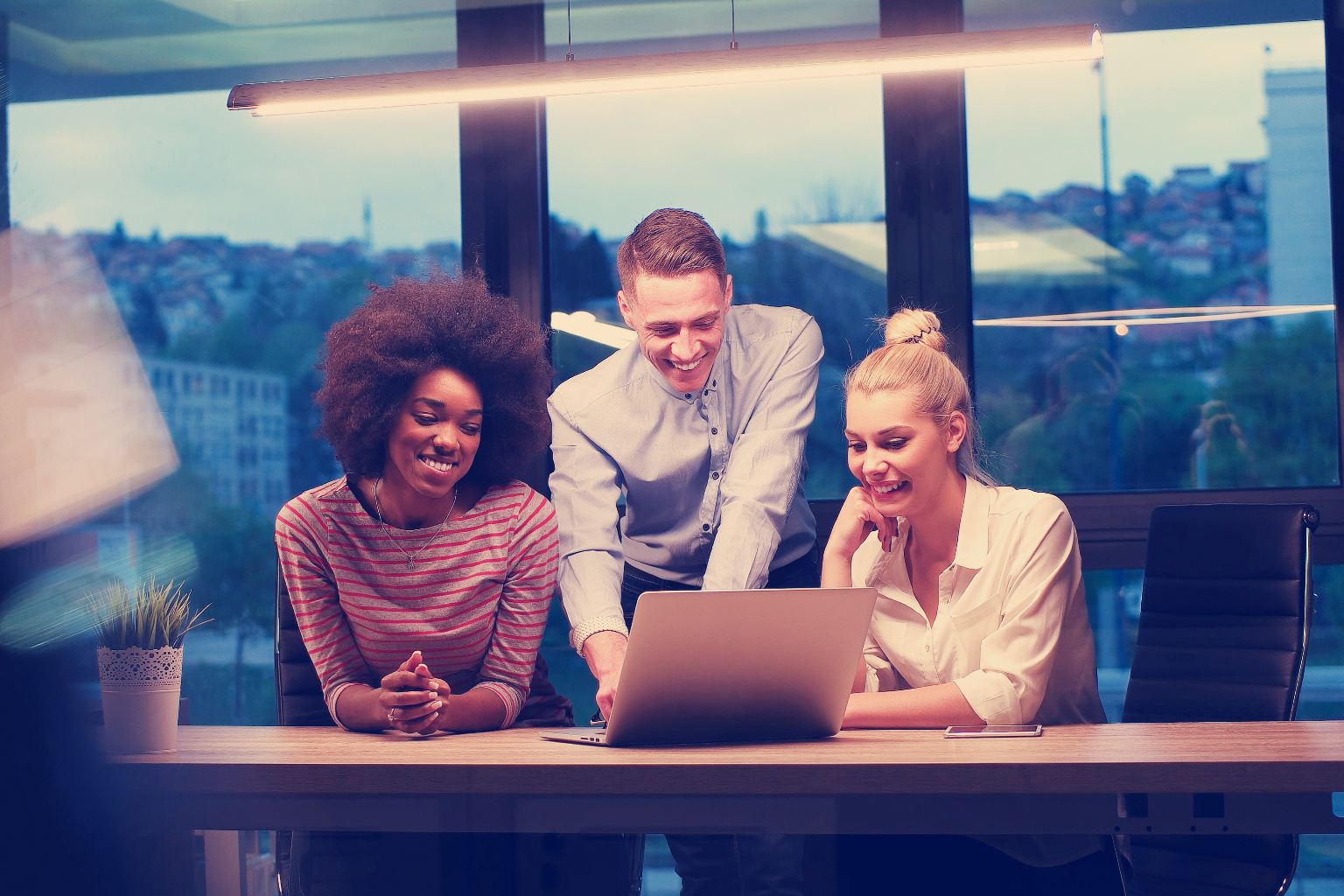 A group of employees gathered around a computer, experiencing increased satisfaction thanks to tax workflow automation