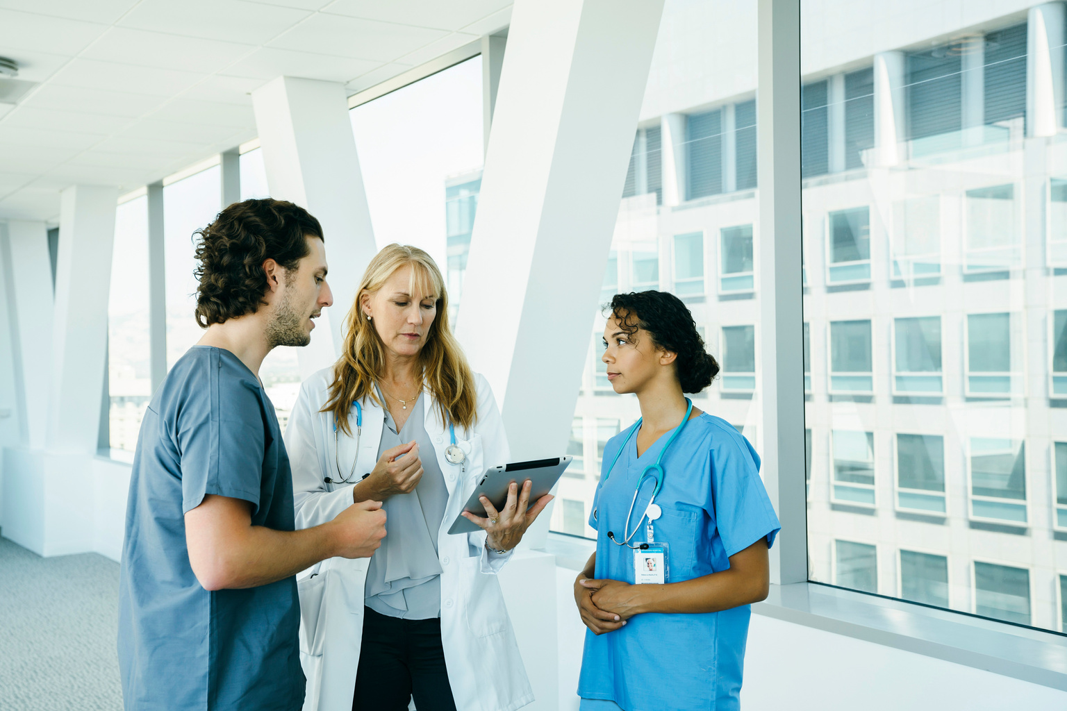 Female doctor with tablet speaking with clinicians in hospital