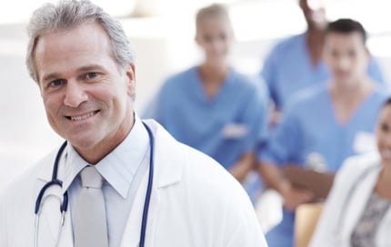 Medical director in foreground with group of healthcare professionals seated in background