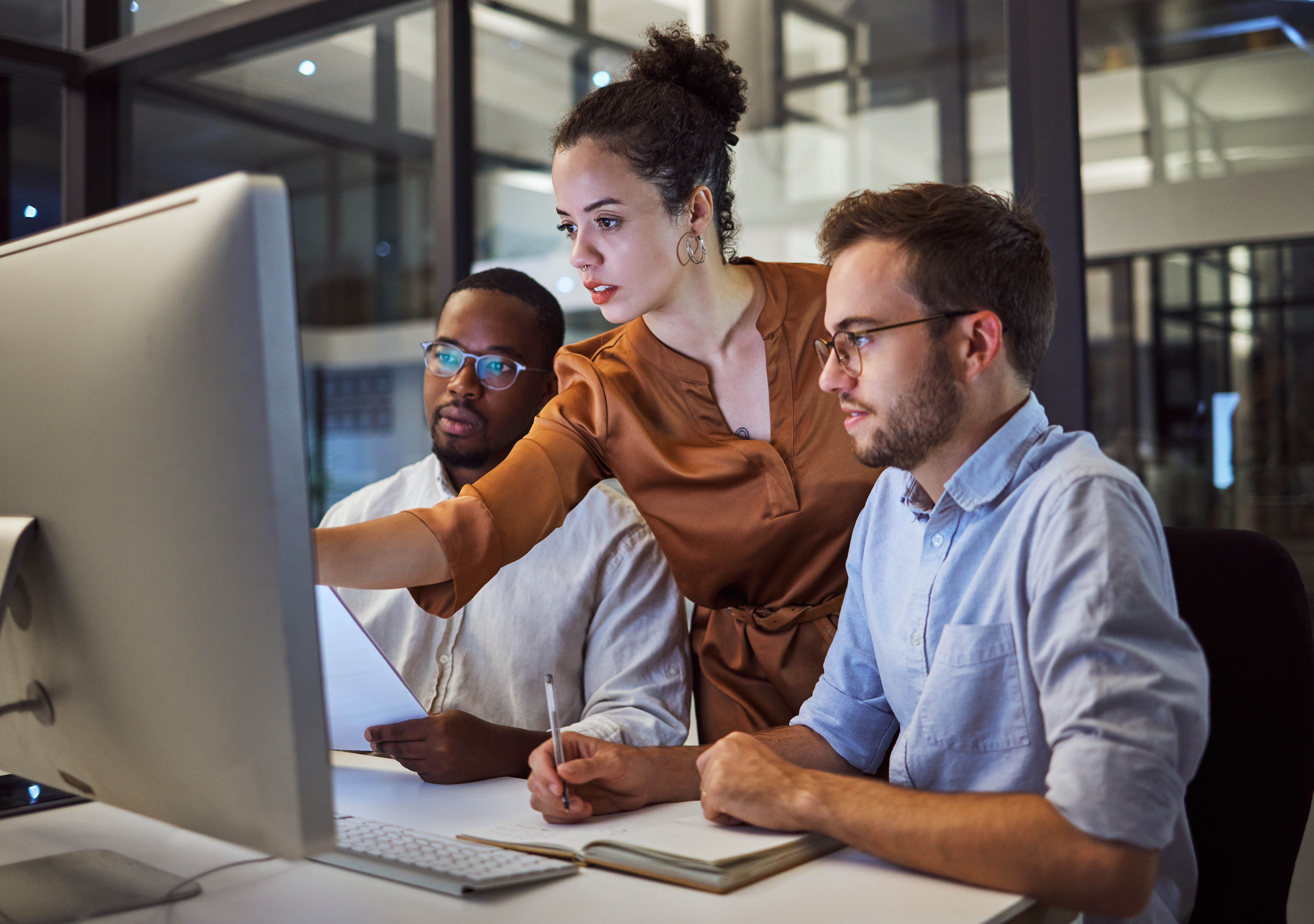 Three people in a business setting working together on a computer