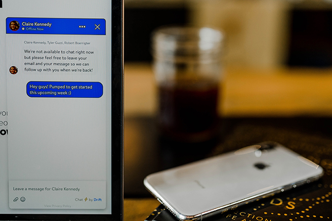 Smartphone with messaging app open in foreground, table in background with drink and another smartphone lying face down