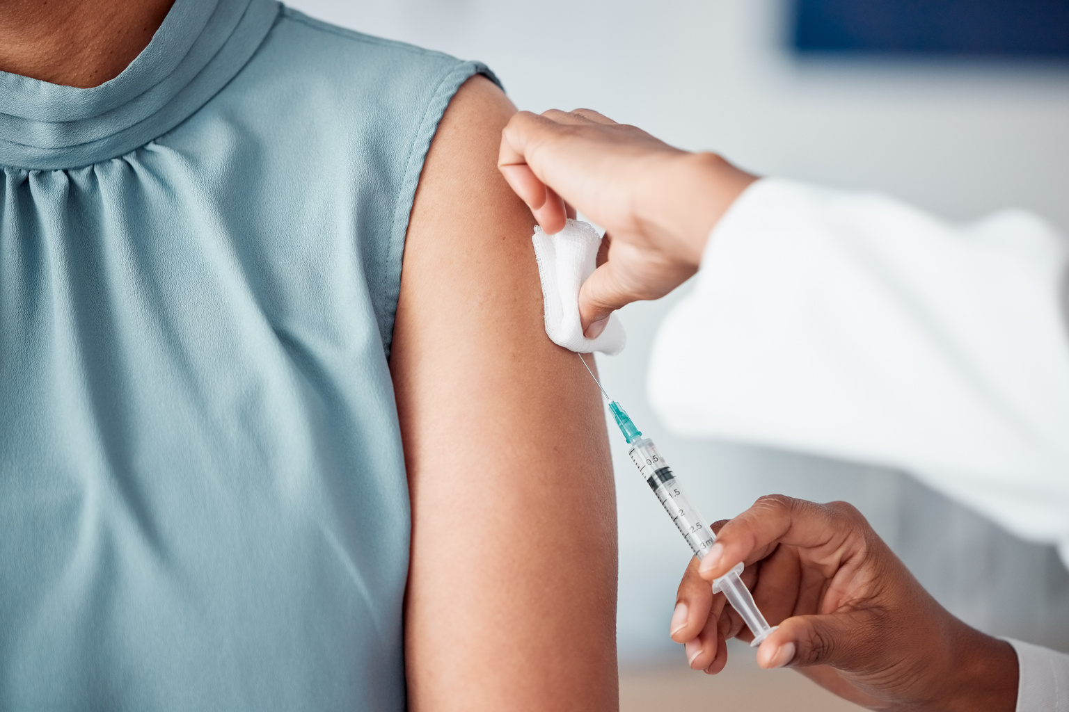 Closeup of a nurse doing a vaccination injection with a needle syringe in a medical office