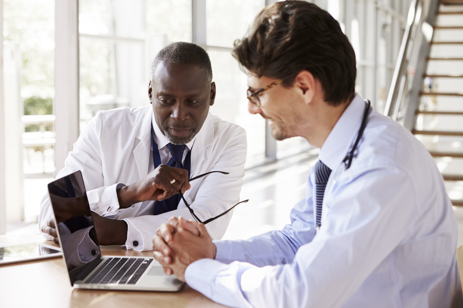 Two doctors having discussion while looking at laptop