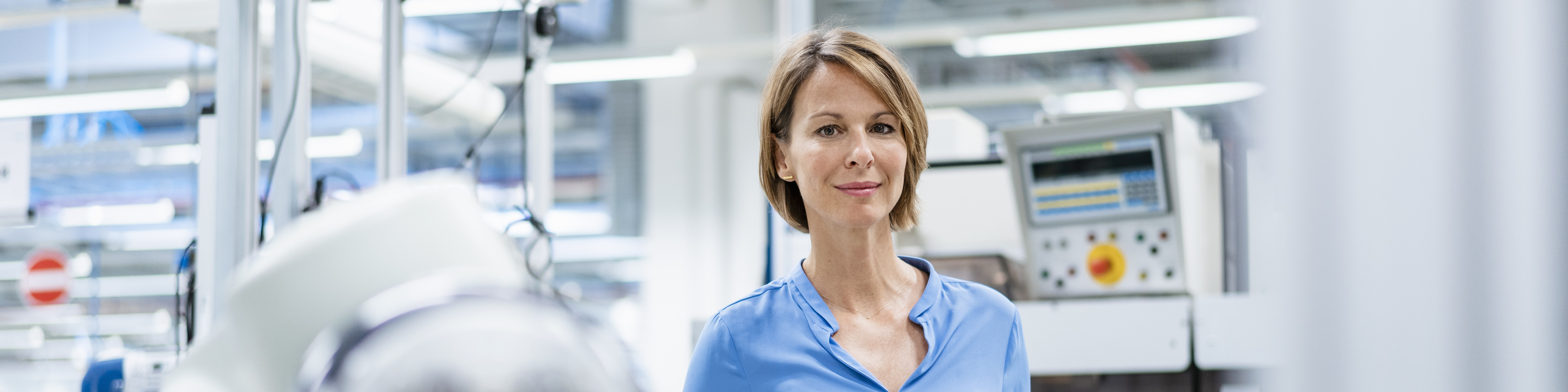 Portrait of businesswoman at assembly robot in a factory