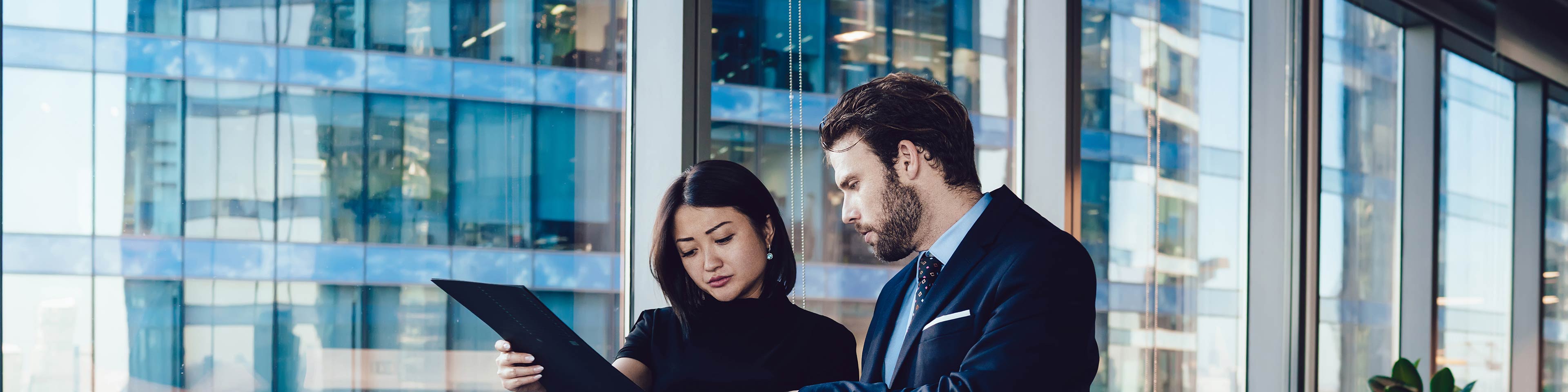 Two business people reviewing a document while walking in the office