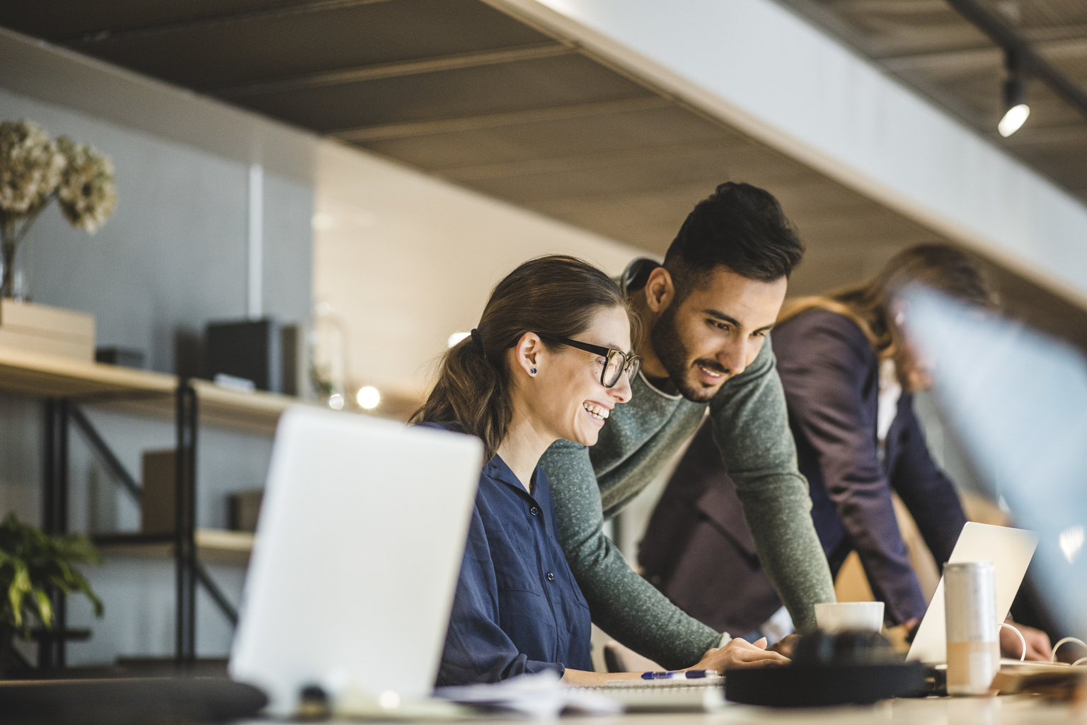 Coworkers smiling and working in a creative business with open office space.