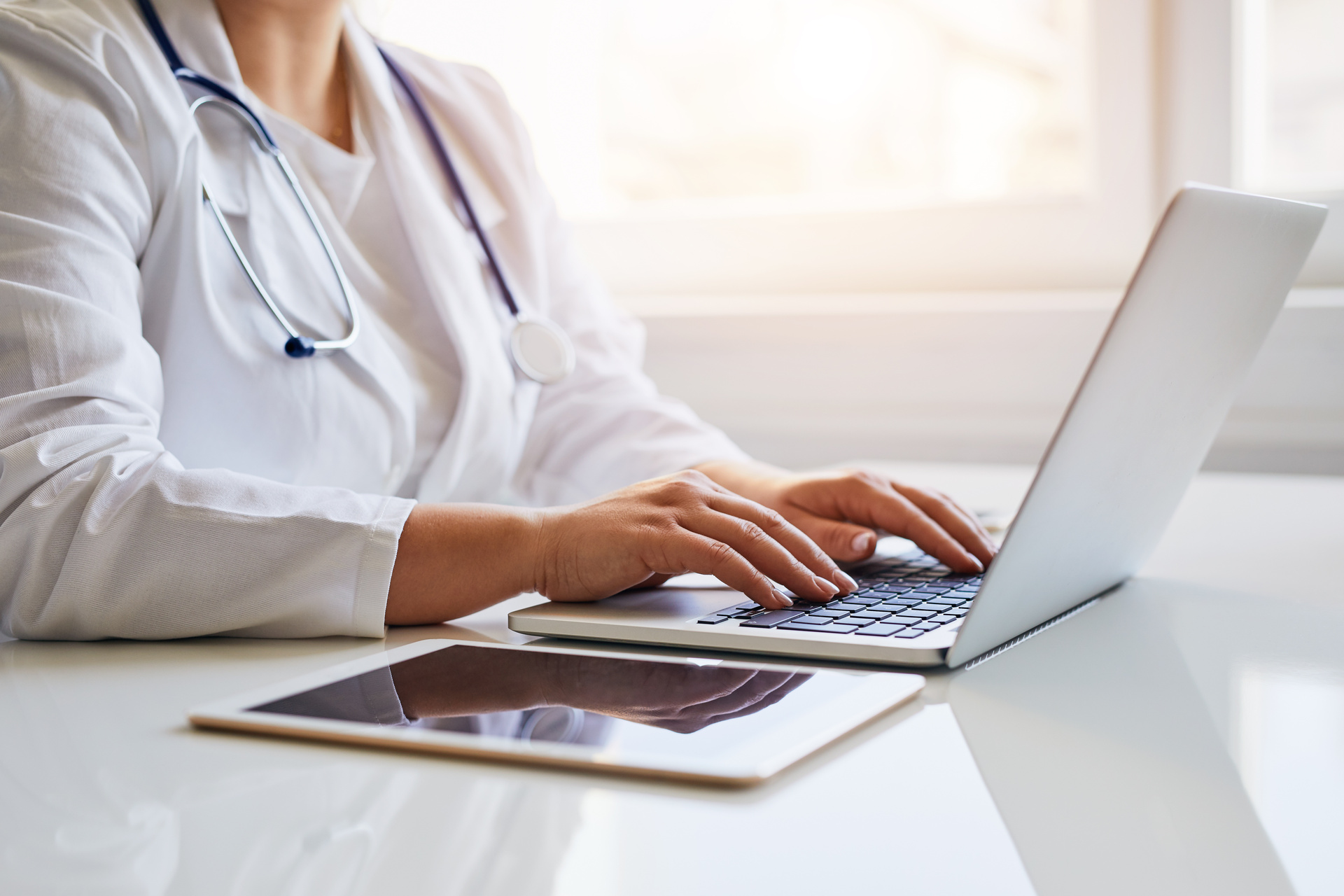 Close up view of a medical professional typing on laptop