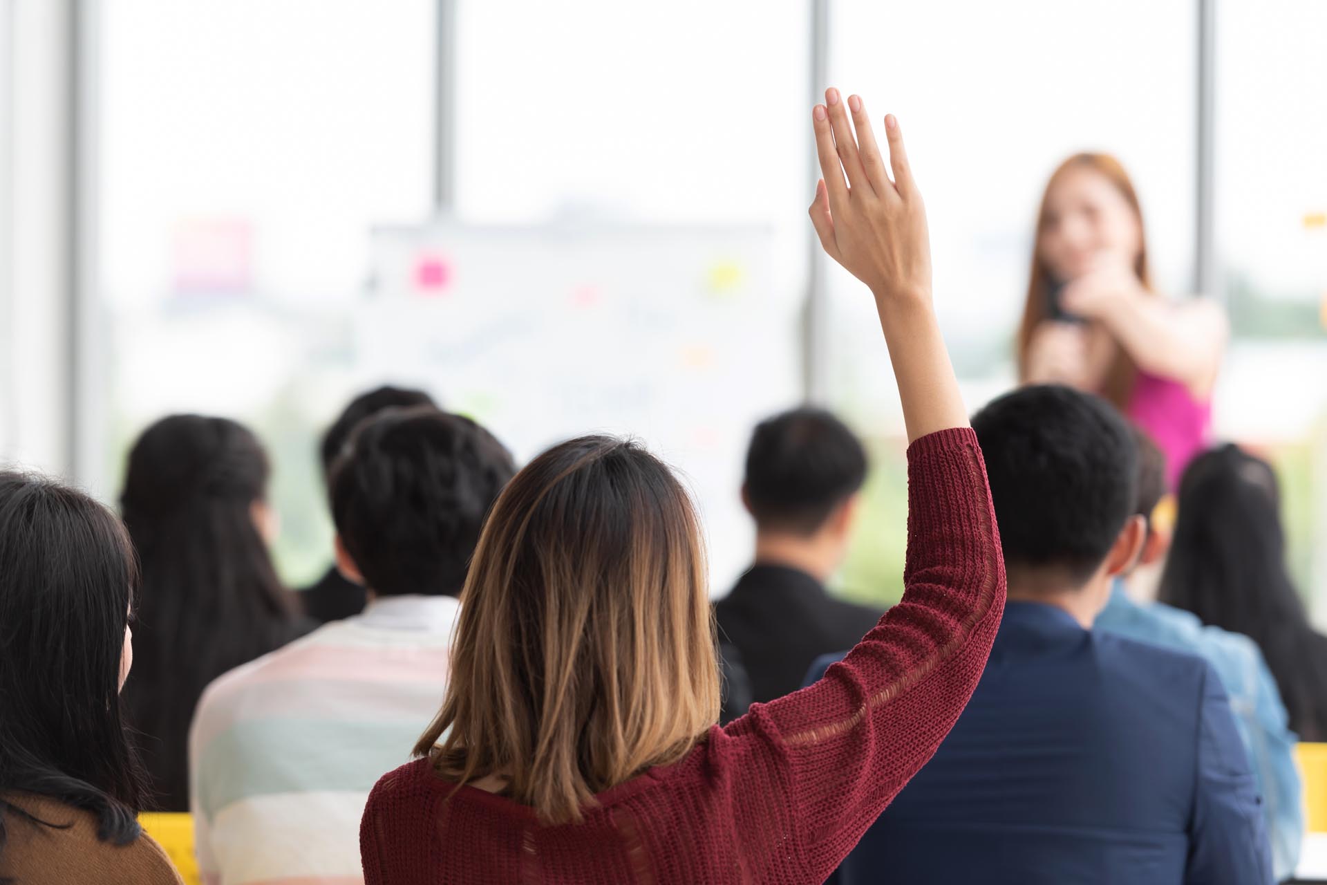 woman in a classroom has her hand raised