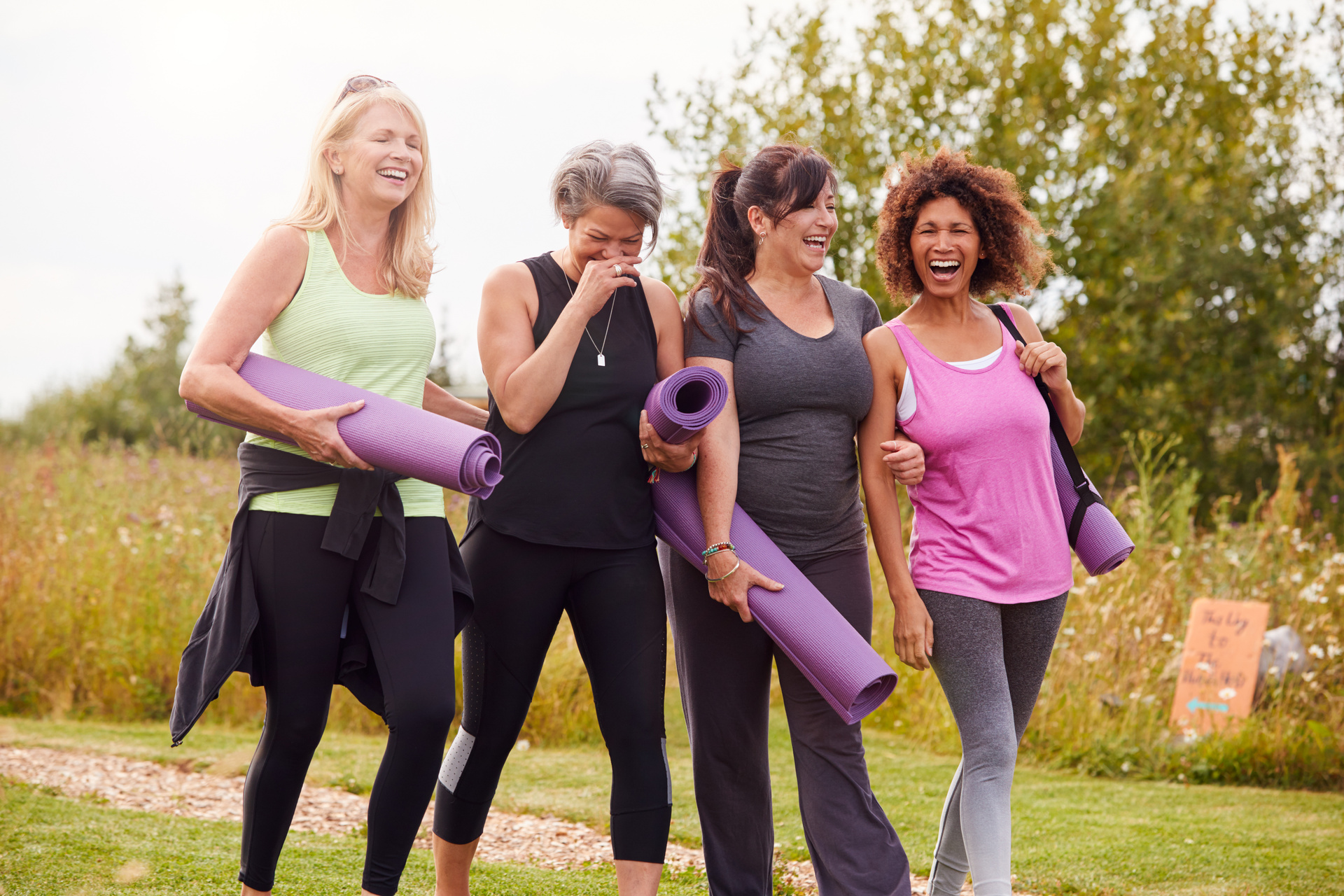 Four mature women walking to yoga practice wearing yoga pants and carrying mats