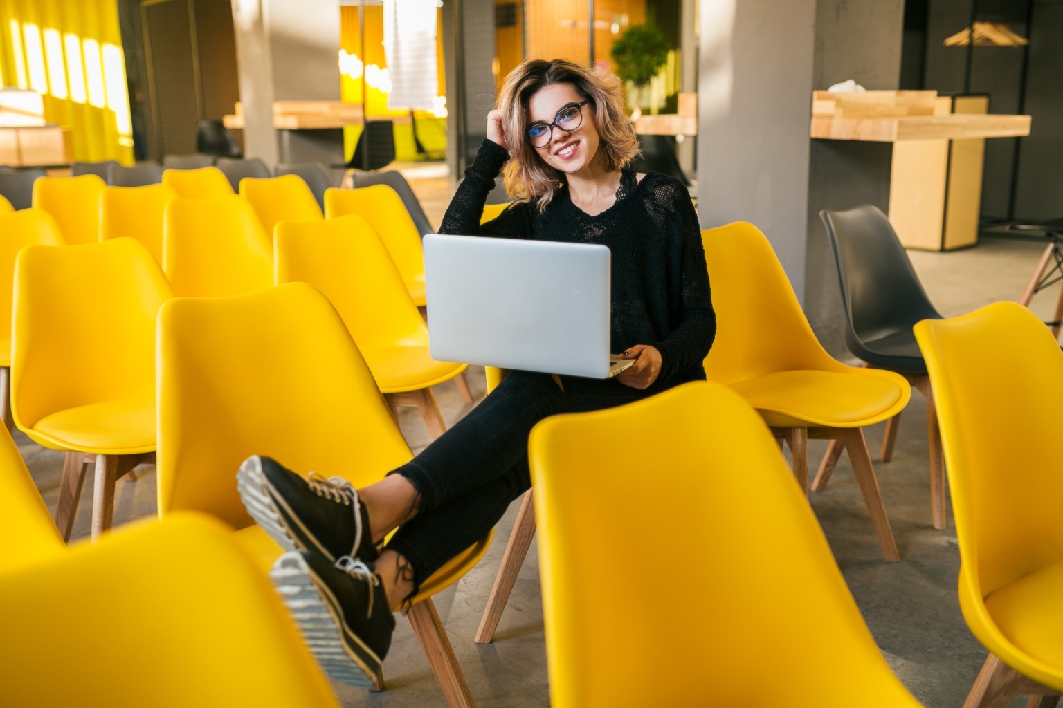 Woman with laptop on yellow chairs
