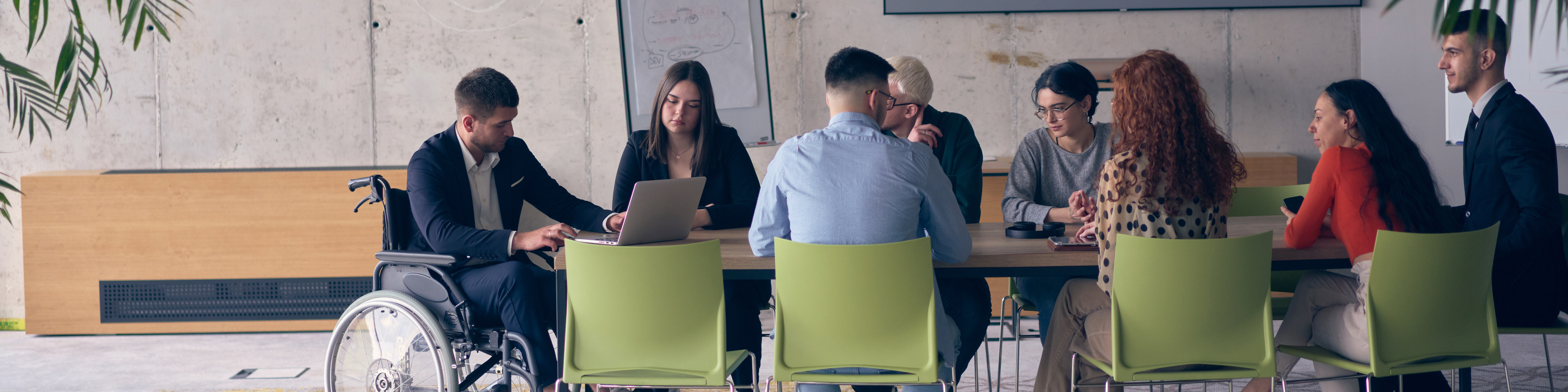 A diverse group of business professionals, including an person with a disability, gathered at a modern office