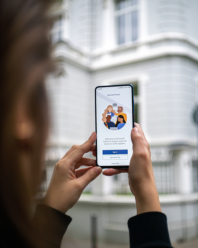 Woman holding up mobile with Microsoft Teams app on the screen