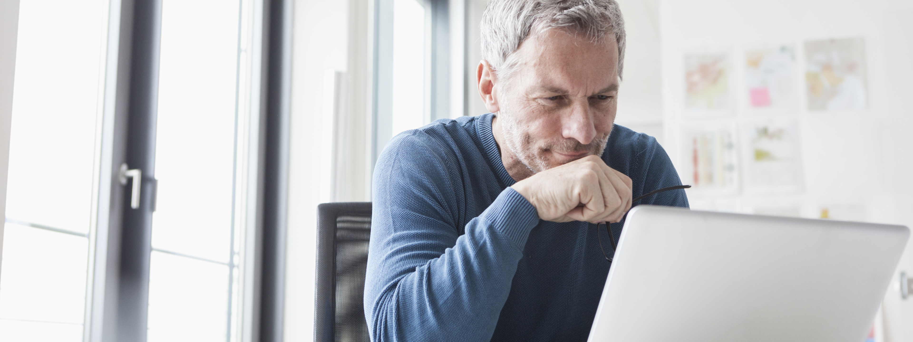 Man with blue long sleeve shirt at computer, Login to Your Wolters Kluwer