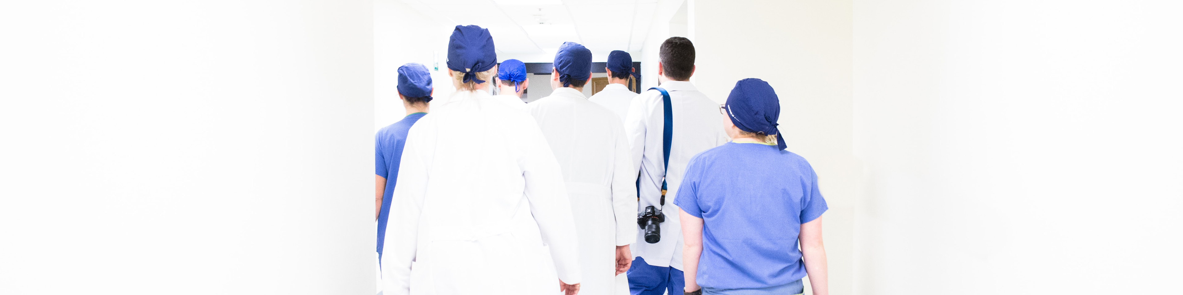Medical team walking down hallway away from camera