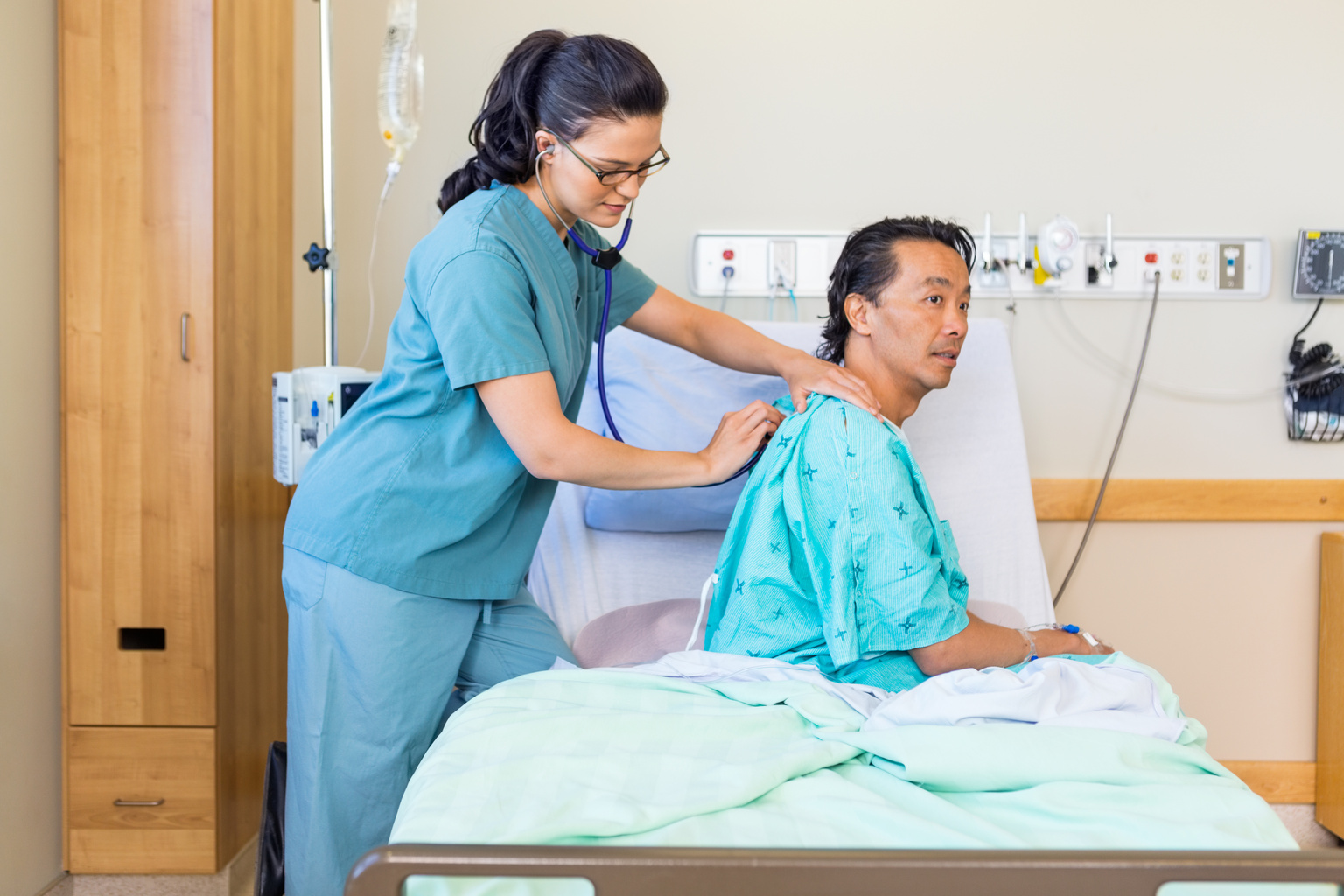 A nurse listening to patient lung and heartbeat using stethoscope in the hospital