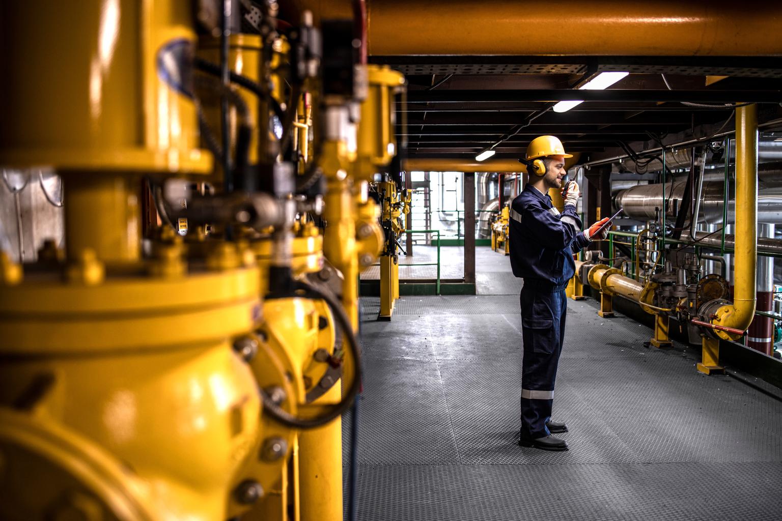 Petrochemical worker controlling process of crude oil production inside oil and gas refinery plant.