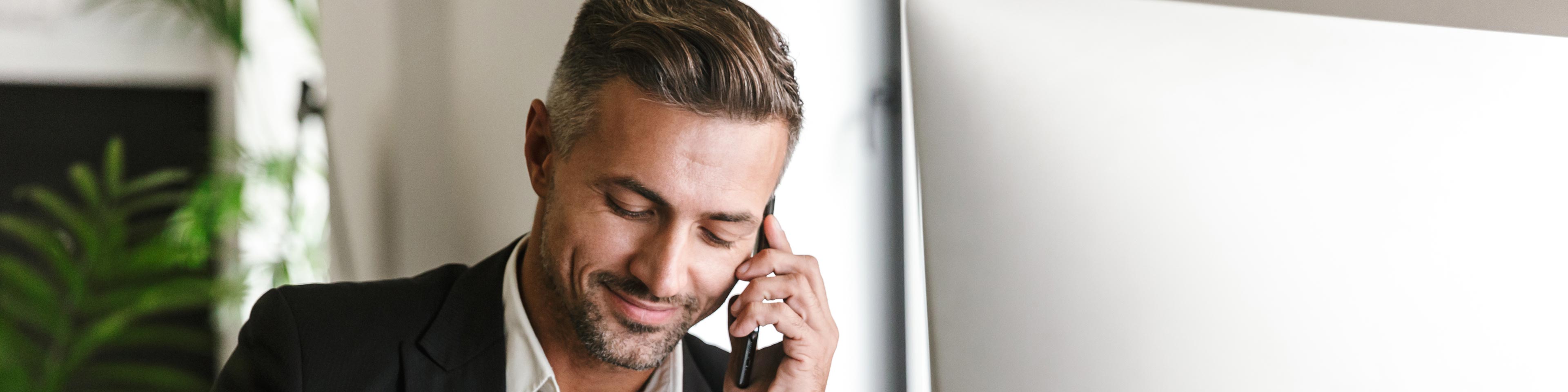 businessman on his cell phone taking notes at his desk