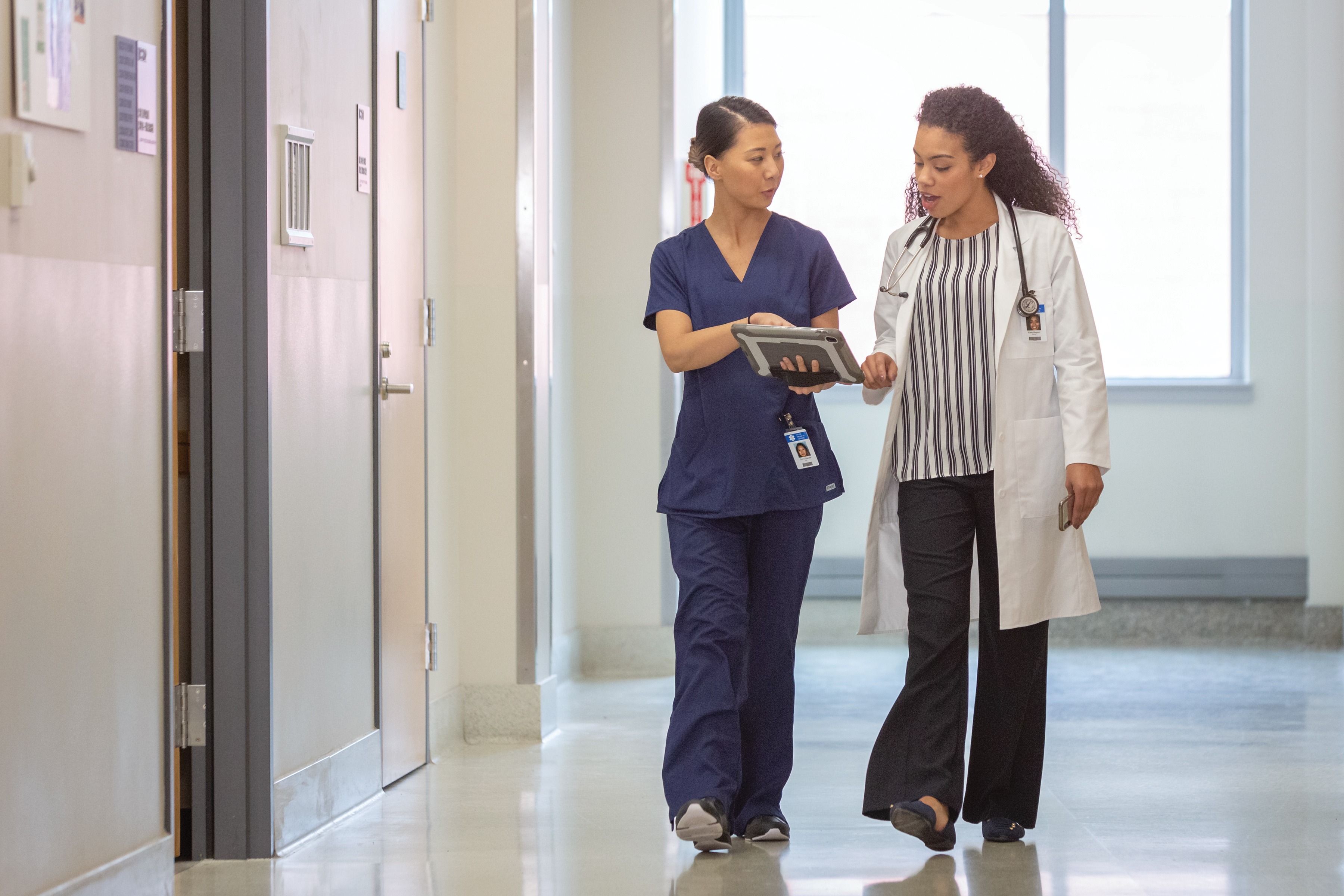 nurse and clinician walking and referring to tablet