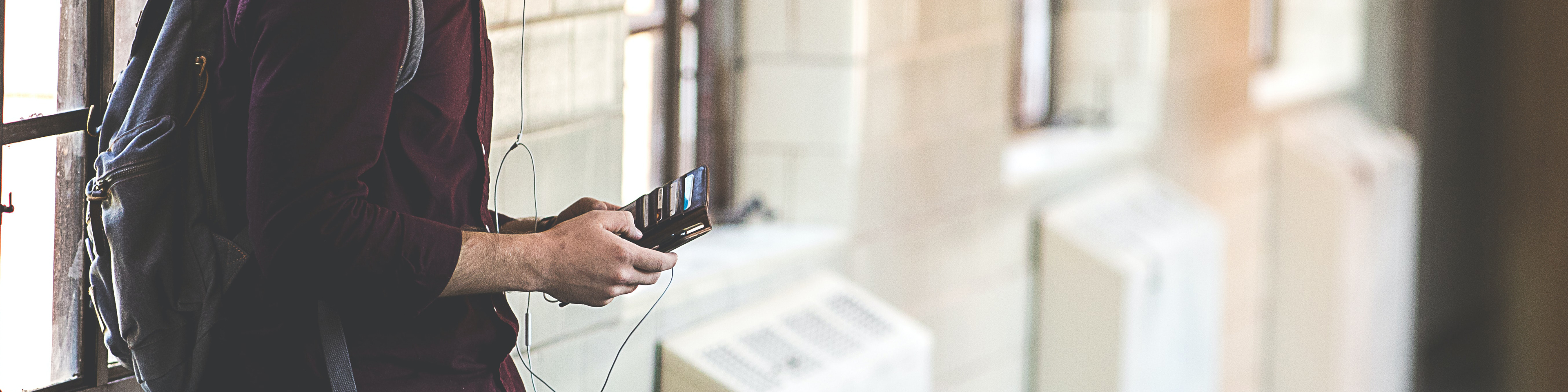 High level school student leaning against window looking at phone