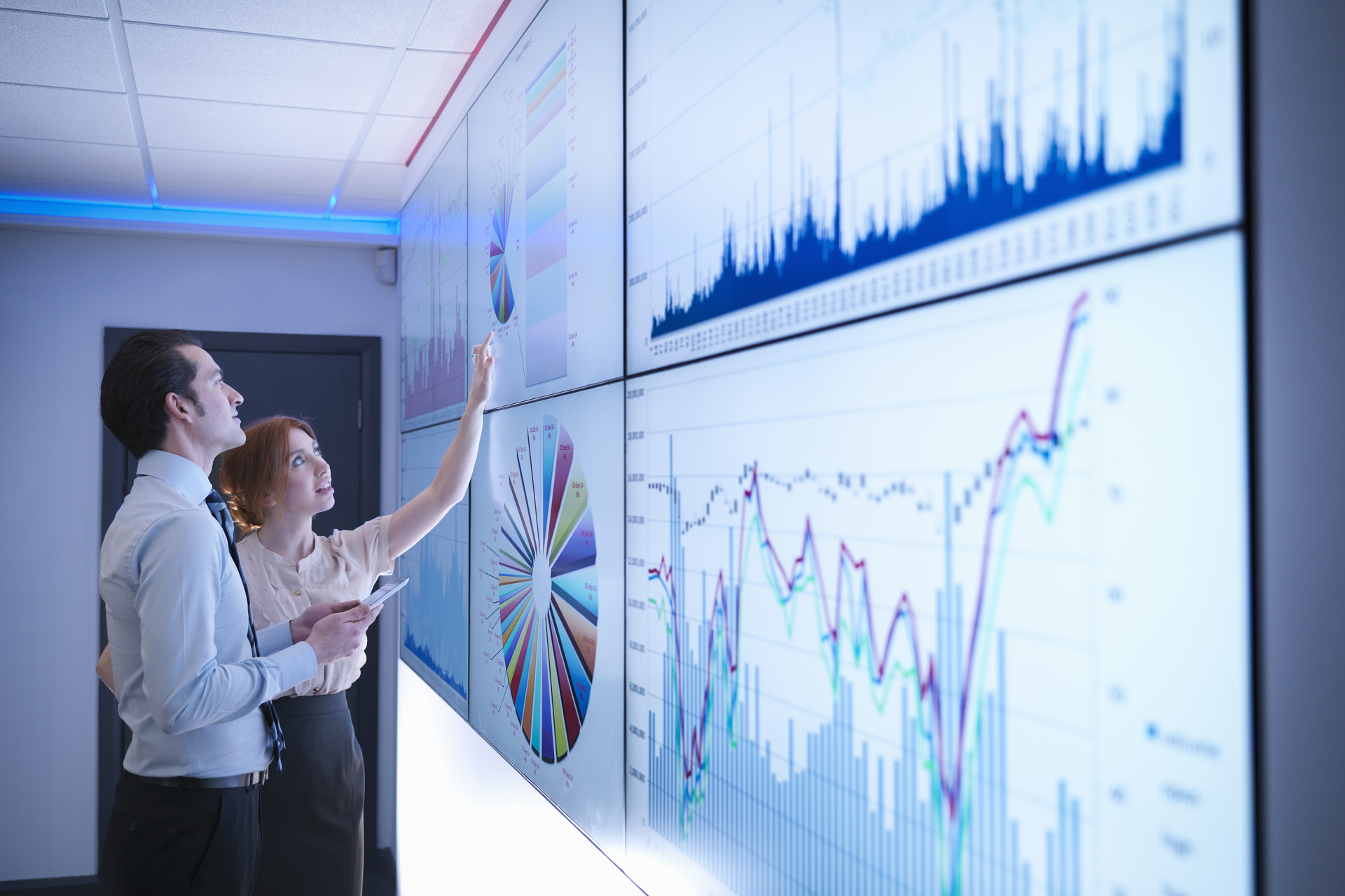 Business colleagues studying graphs on screen in meeting room