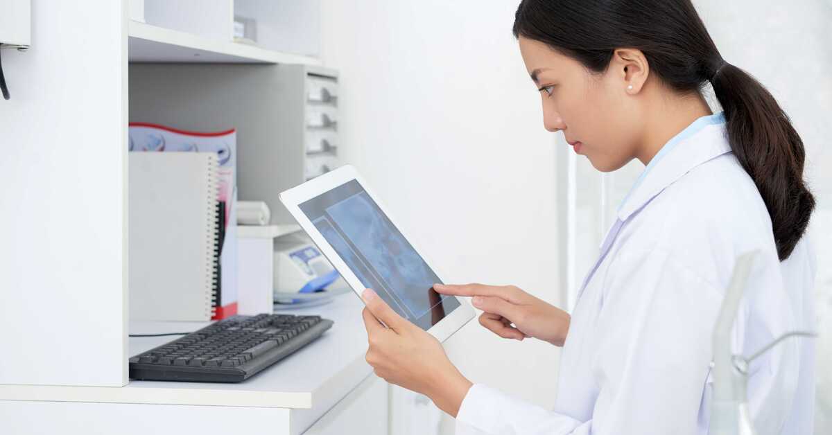 Female doctor sitting at desk holding tablet