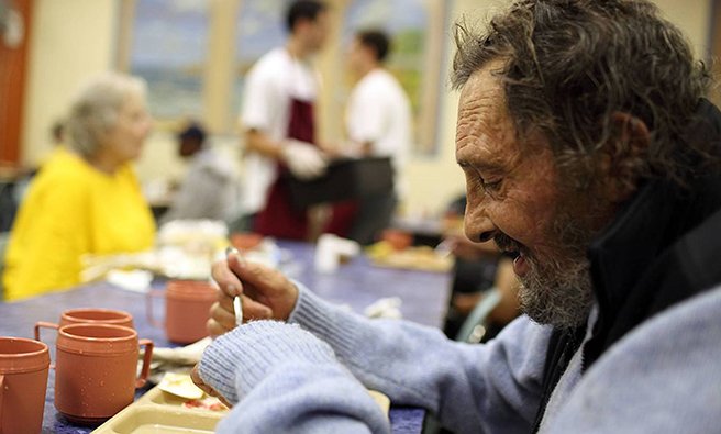 A homeless man eating a meal at a soup kitchen