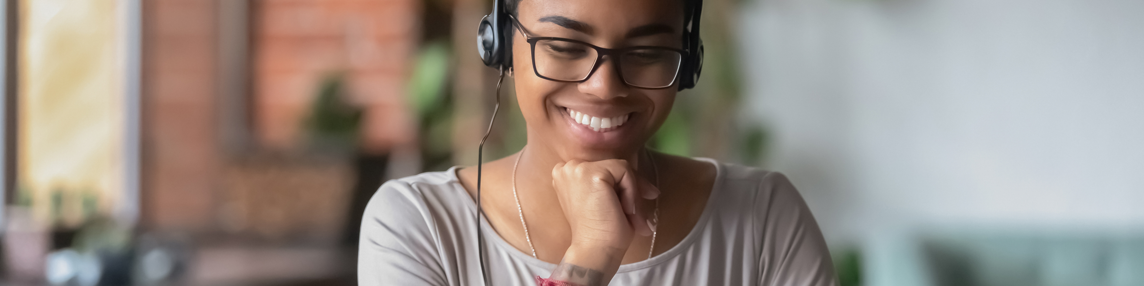 Woman wearing headphones, looking at laptop screen