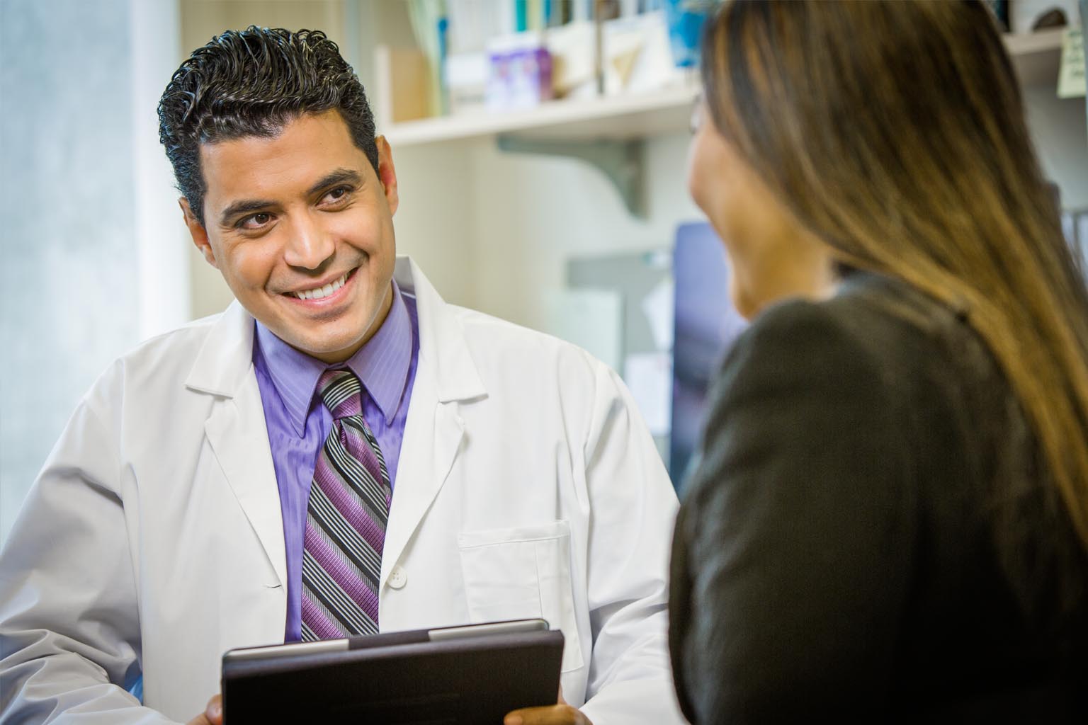 male doctor with tablet talking to female patient