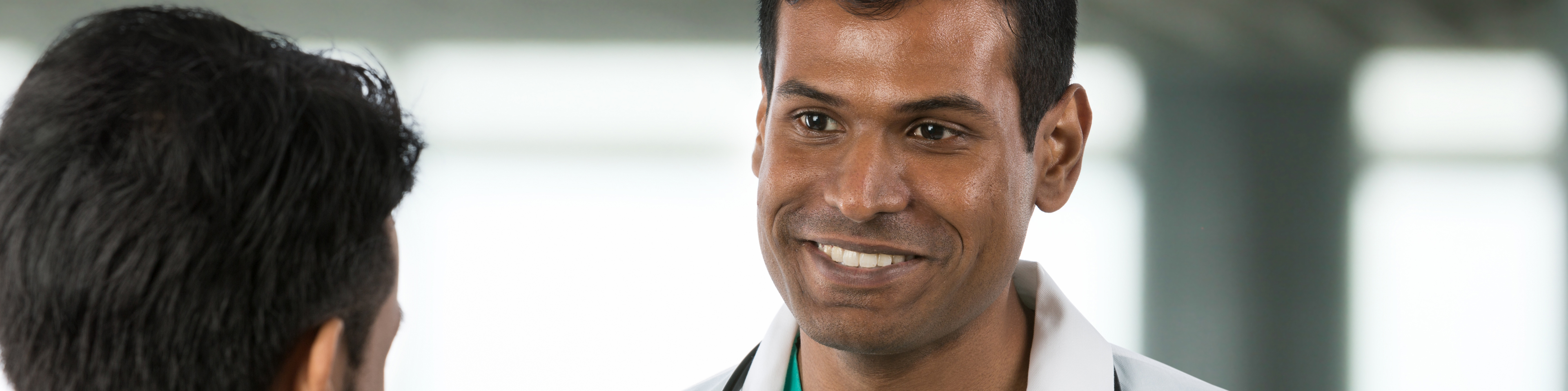 Doctor standing with and smiling at patient in open hospital area