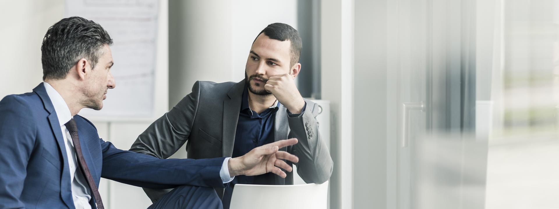 Two businessmen talking in office at the window