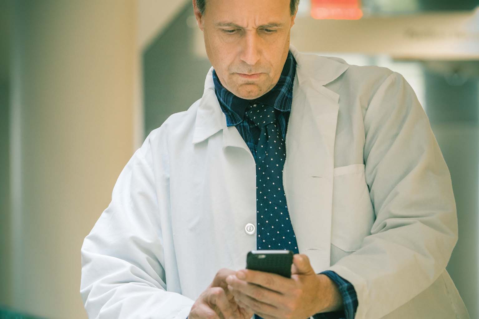 doctor paused in hallway looking at smartphone