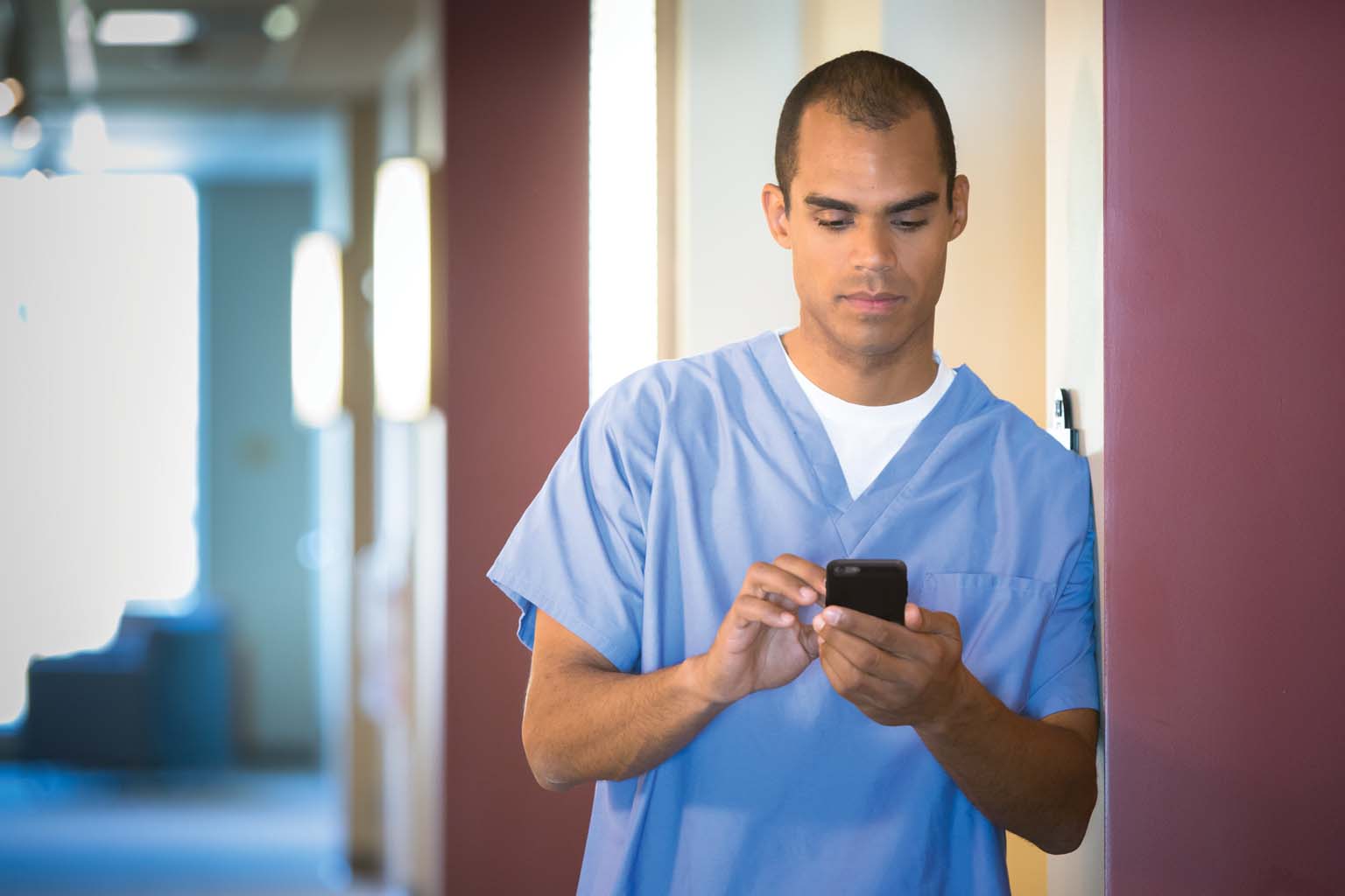 doctor paused in hallway looking at smartphone
