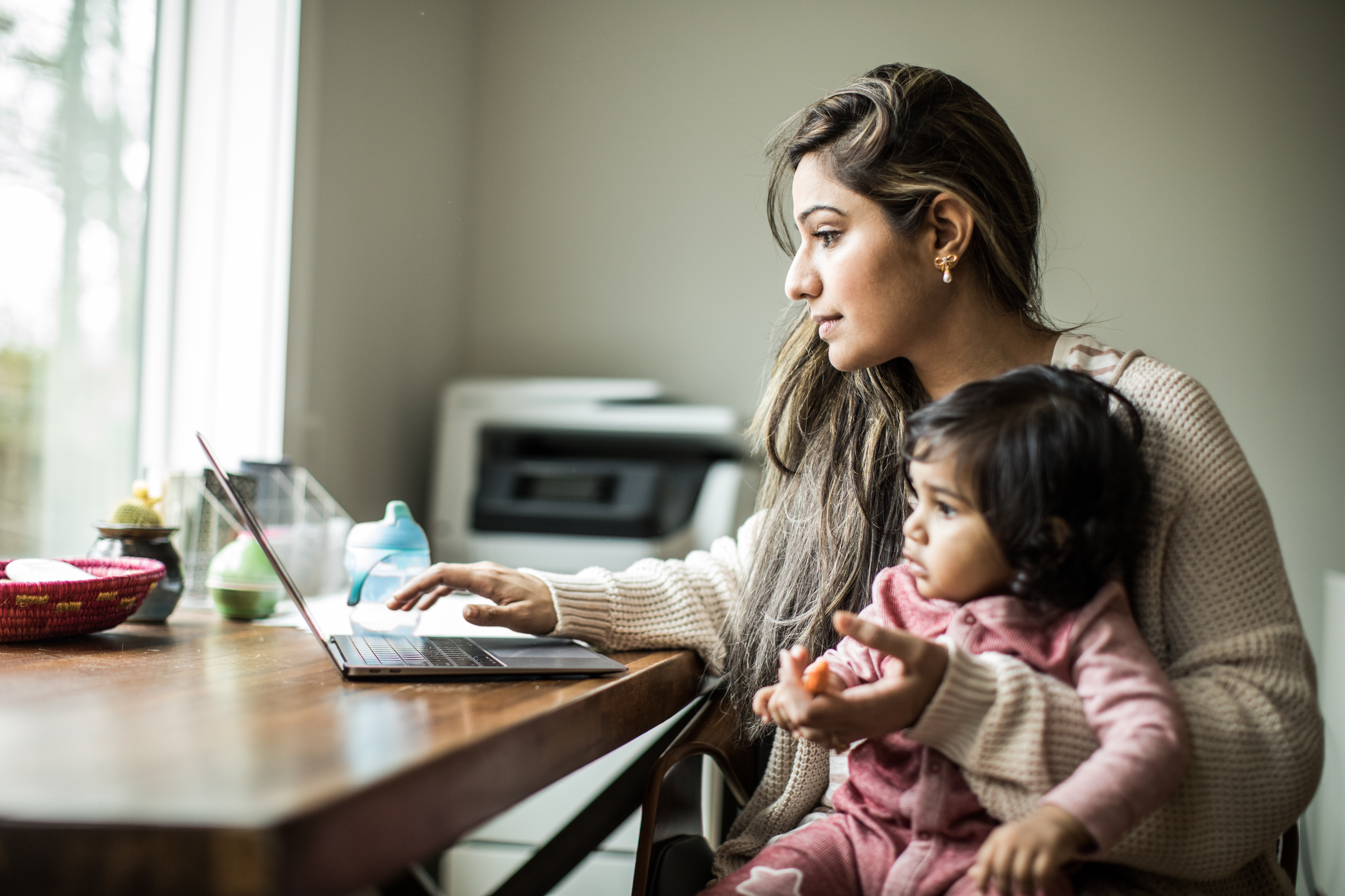 woman working on the computer and holding her daughter, little girl, with pink onesie, q3 2021, TAA NA US - Preparer