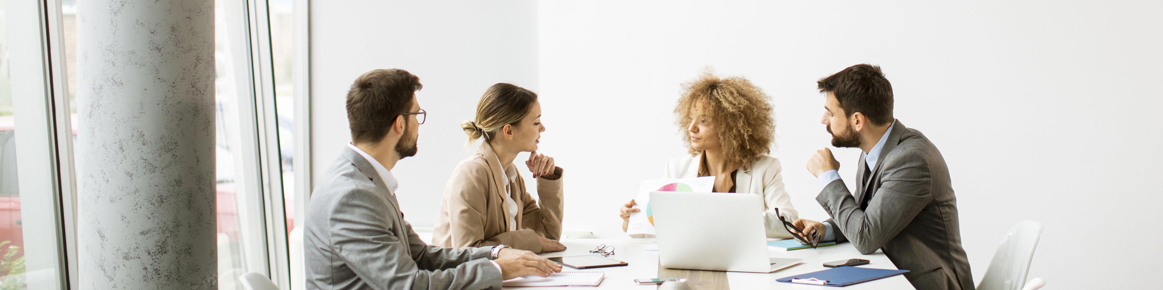 two businessmen and two businesswomen in a conference room meeting