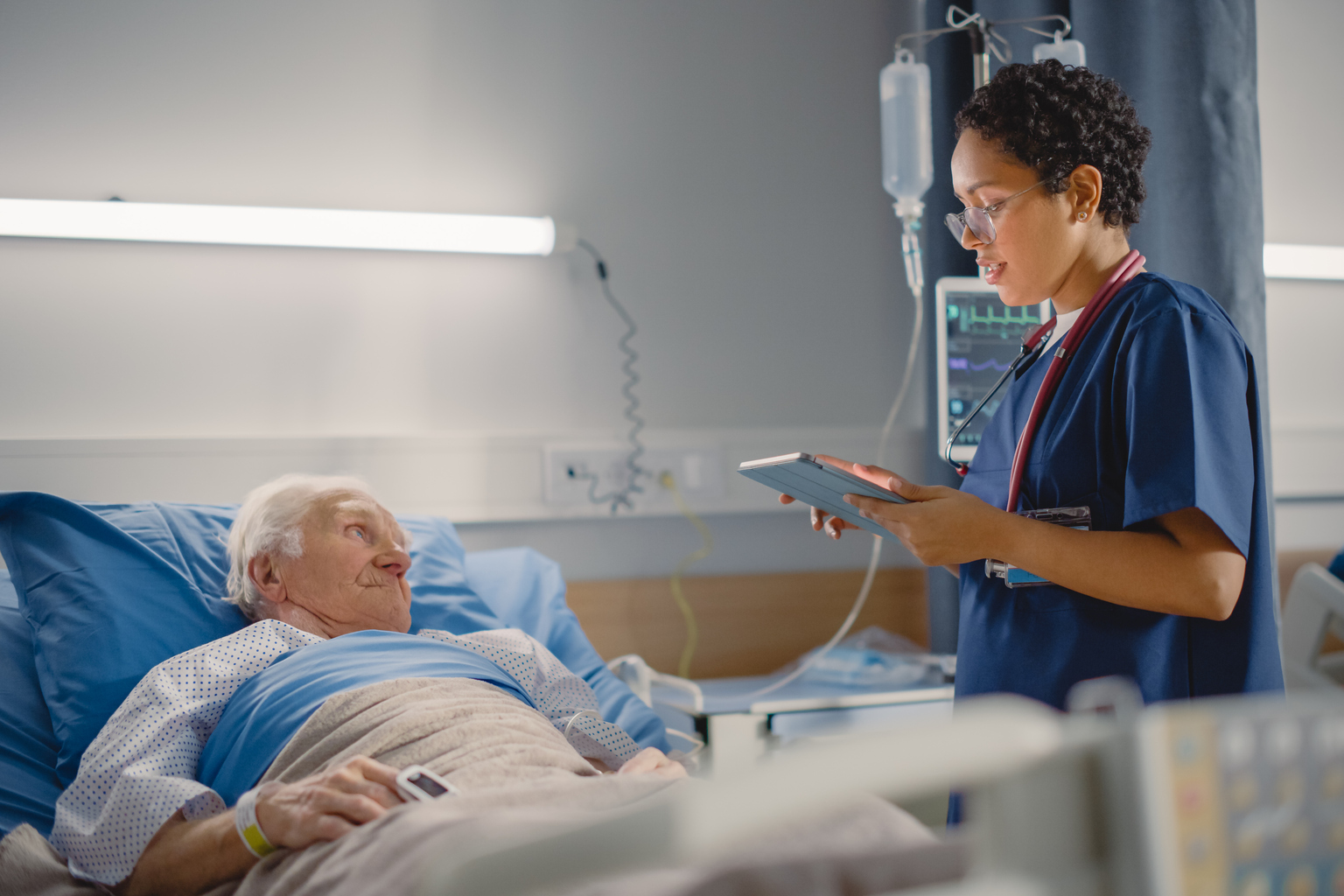 Nurse with older male patient in bed in the recovery room