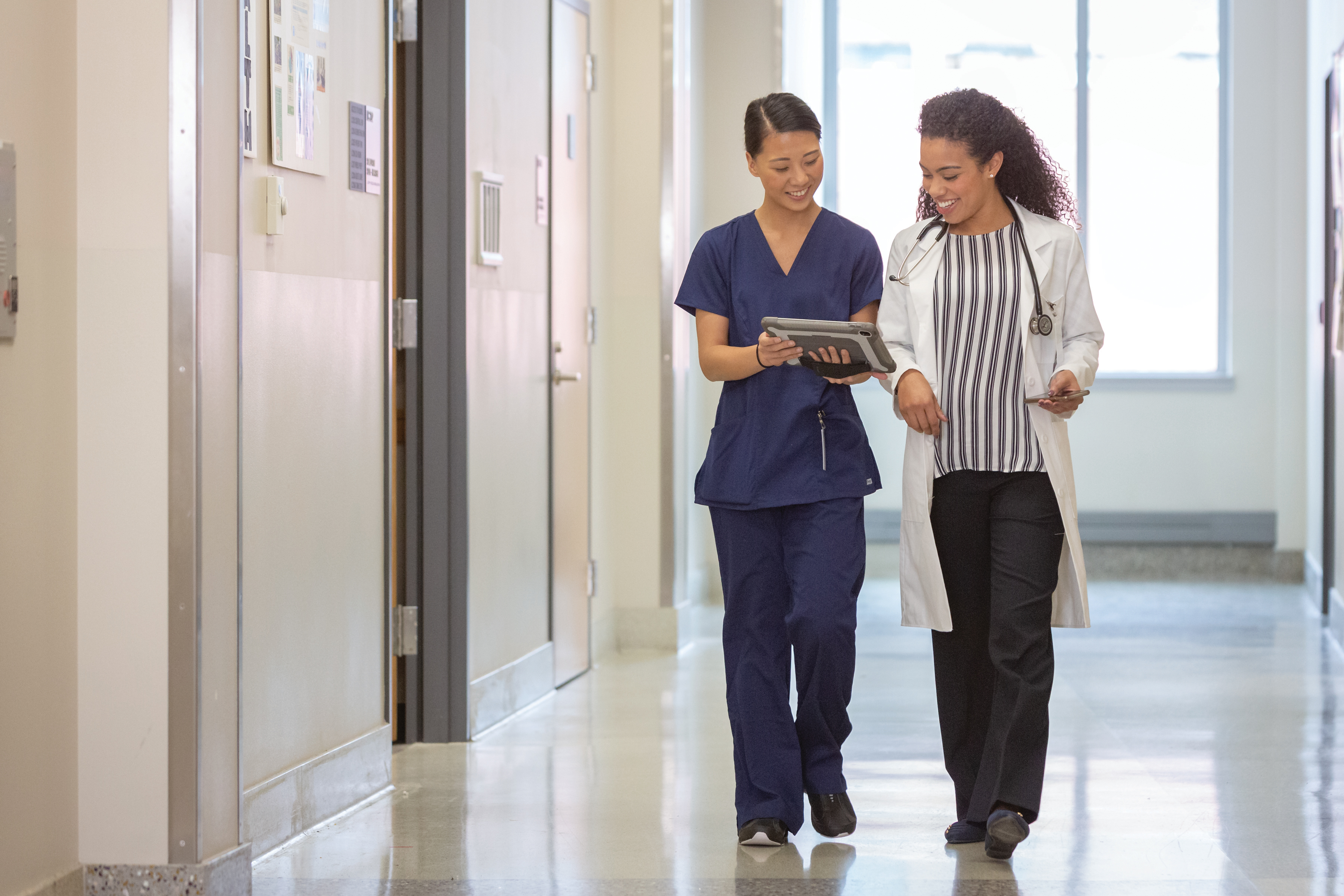 nurse and clinician walking and referring to tablet