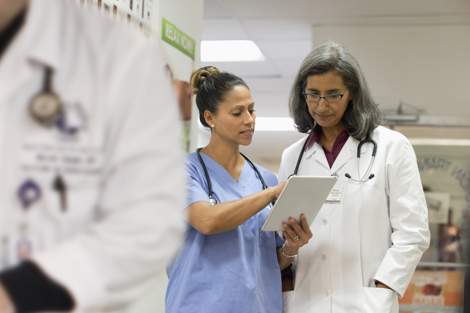 Mixed Race doctor talking to nurse with digital tablet